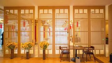 A room with a wooden floor, a dining table with chairs, and a decorative partition with vertical slats.