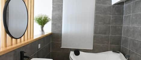 A modern bathroom with a freestanding bathtub, a large mirror, and a wooden vanity.
