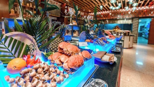 Een buffet met zeevruchten, tropische planten en een houten plafond.