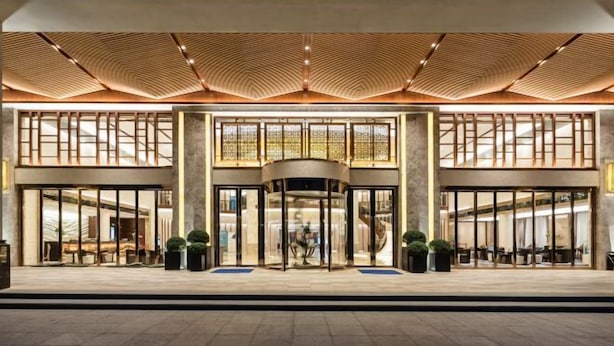 Entrada de hotel con puerta giratoria, ventanas amplias y un diseño moderno en el techo.