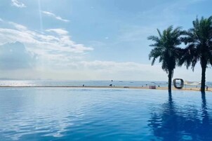 Vista despejada de una piscina con una palmera y una playa a lo lejos.