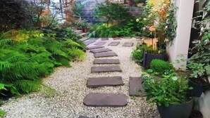 Ein Gartenpfad mit trittfesten Steinen, der durch üppiges Grün führt.