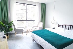 A hotel room with a bed, a chair, a desk, and a large window with curtains. - July 3rd (Fenghuang County)