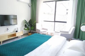 A modern hotel room with a bed, a TV, a desk, a chair, and a large window. - July 3rd (Fenghuang County)