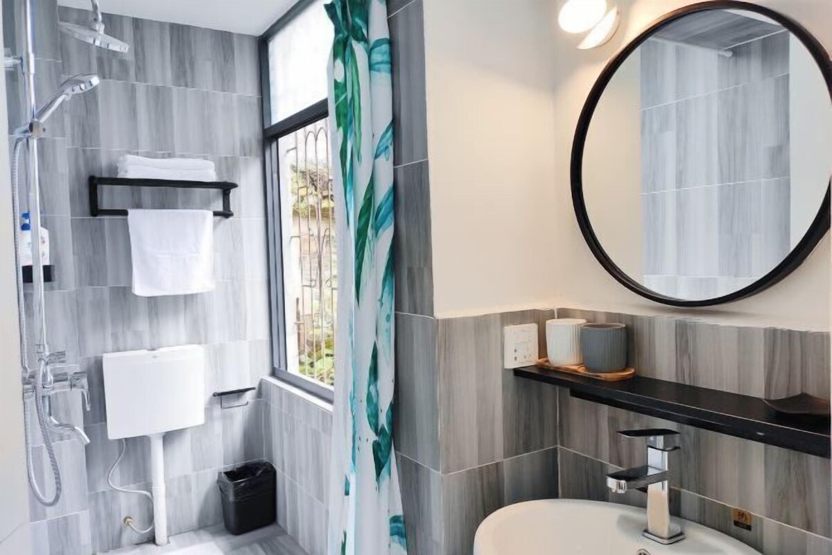A modern bathroom with a shower, toilet, sink, and a large mirror.