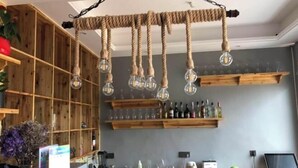 A kitchen with wooden shelves, hanging light bulbs, and a laptop on the counter. - 37 Degree Grey Homestay in Wenzhou (Wenzhou)