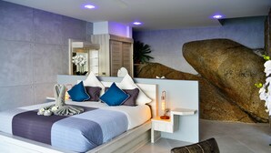 Ein modernes Schlafzimmer mit einem großen Bett, einem Nachttisch und einer großen Felsformation an der Wand.