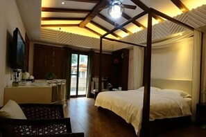 A bedroom with a canopy bed, a sitting area with a sofa, and a desk with a chair. - Gujian Yunhai Hotel (Chongqing)
