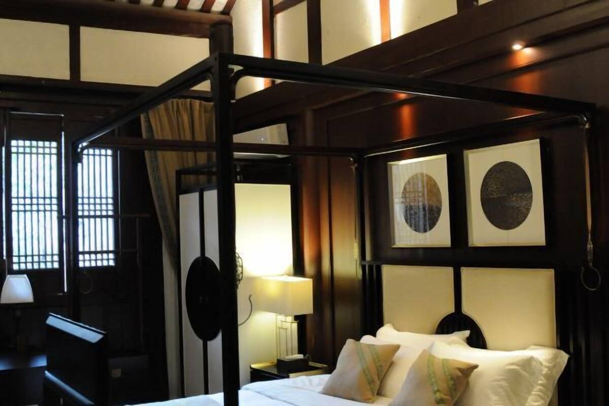 A traditional four-poster bed with a headboard, bedside tables, and a lamp.