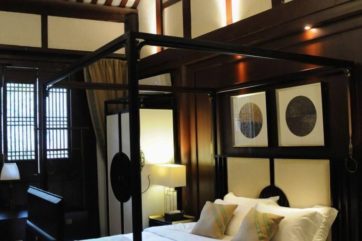 A traditional Japanese-style room with tatami flooring, a low wooden bed, and shoji screens.