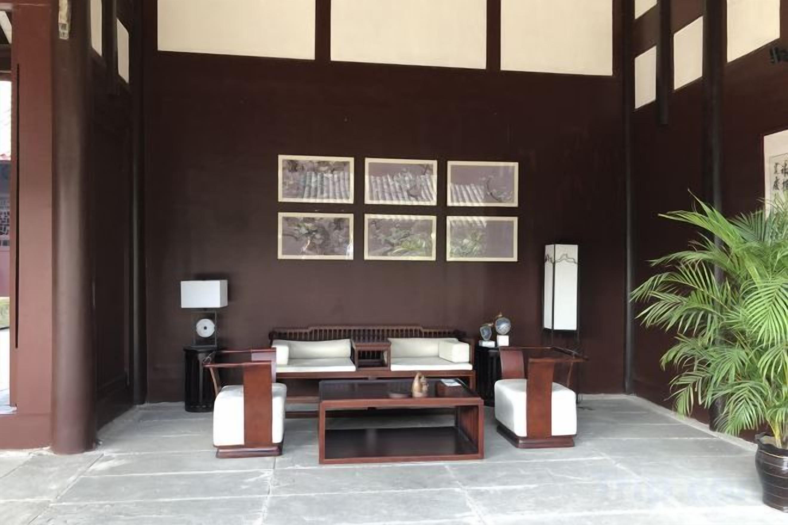 A reception area with a sofa, two side tables, a coffee table, framed pictures on the wall, and a potted plant.