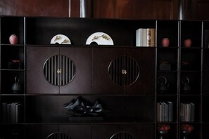 Een donkere houten kast met ronde uitsparingen, planken met boeken en decoratieve objecten.