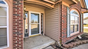 A residential building with a brick facade, a front door with a glass panel, and a small porch area.