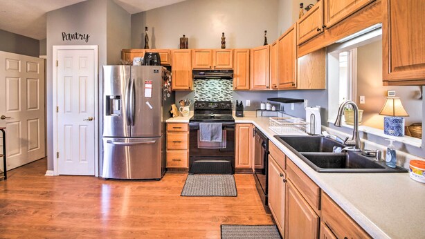 A kitchen with wooden cabinets, a stainless steel refrigerator, an oven, and a sink.