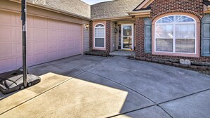 A residential garage with a basketball hoop, a driveway, and a house with a brick facade and arched windows.