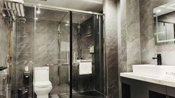 A modern bathroom with a glass-enclosed shower, a white toilet, and a large mirror above a white sink.