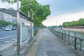 Una acera con un refugio de parada de autobús, un río y un puente al fondo.