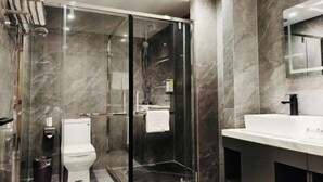 Un baño moderno con ducha envuelta en vidrio, un inodoro blanco y un lavabo con espejo.