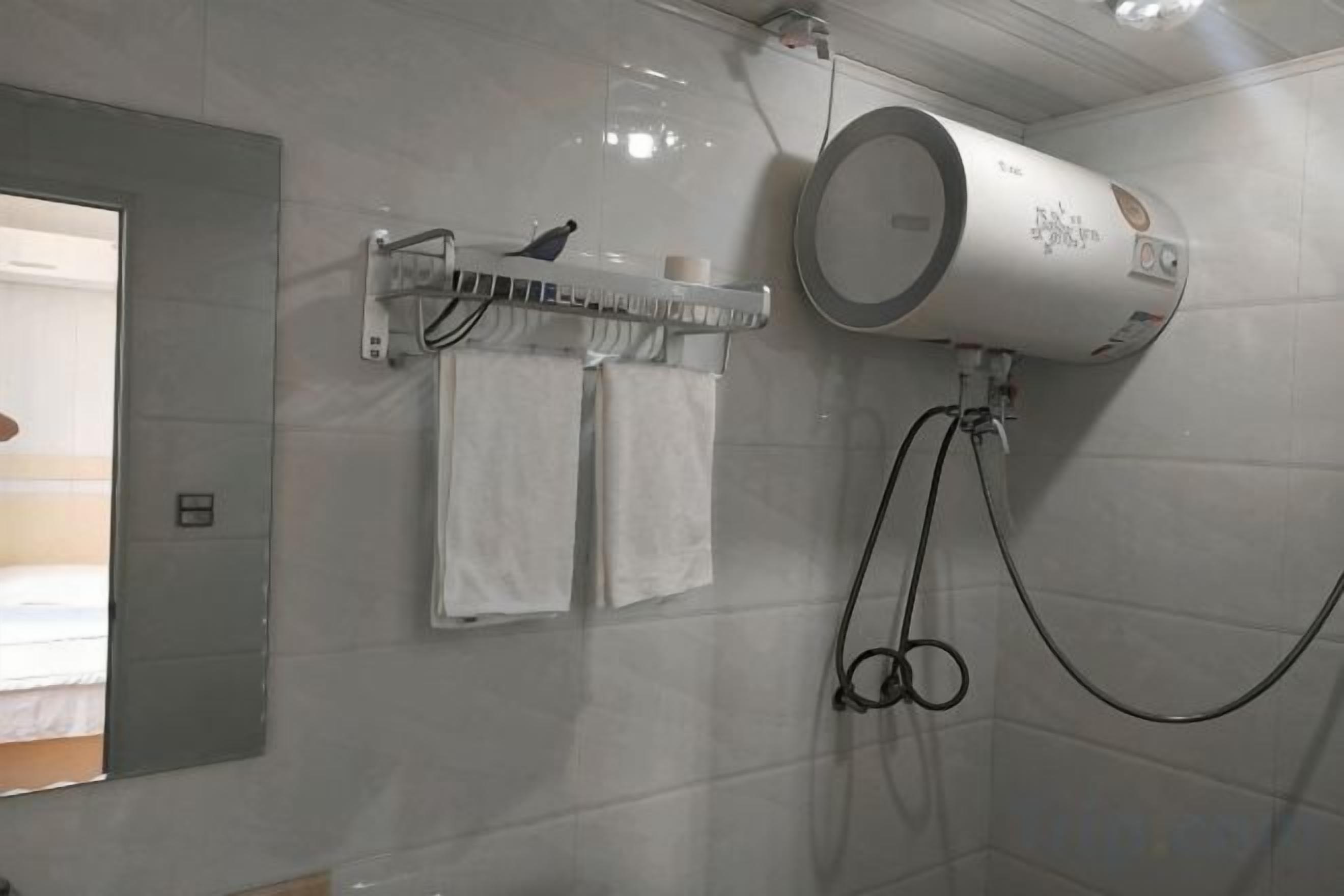 Une salle de bain équipée d’un porte-serviettes où sont rangées deux serviettes, d’un sèche-mains et d’un support à papier toilette fixé au mur.