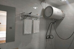 Een badkamer met een handdoekrek met twee handdoeken, een handdroger en een toiletrolhouder aan de muur.