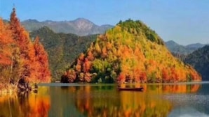 A serene lake with autumn foliage and a small boat. - Xiagu Renjia Hostel (Qianshan)