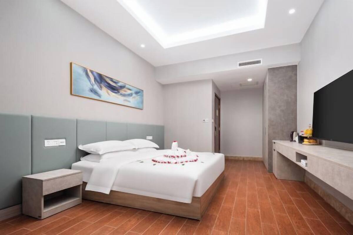 Une chambre à coucher moderne, avec un lit, une table de chevet, des œuvres d’art et un téléviseur.