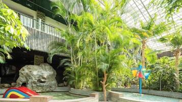 Un atriumo interior con una formación rocosa, palmeras y una estructura de juegos colorida.