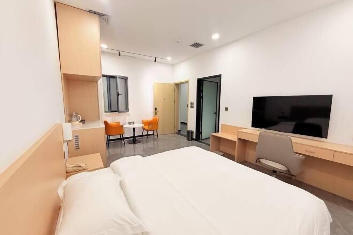 Une chambre d’hôtel avec un lit, un bureau, une chaise, une télévision et une petite table.
