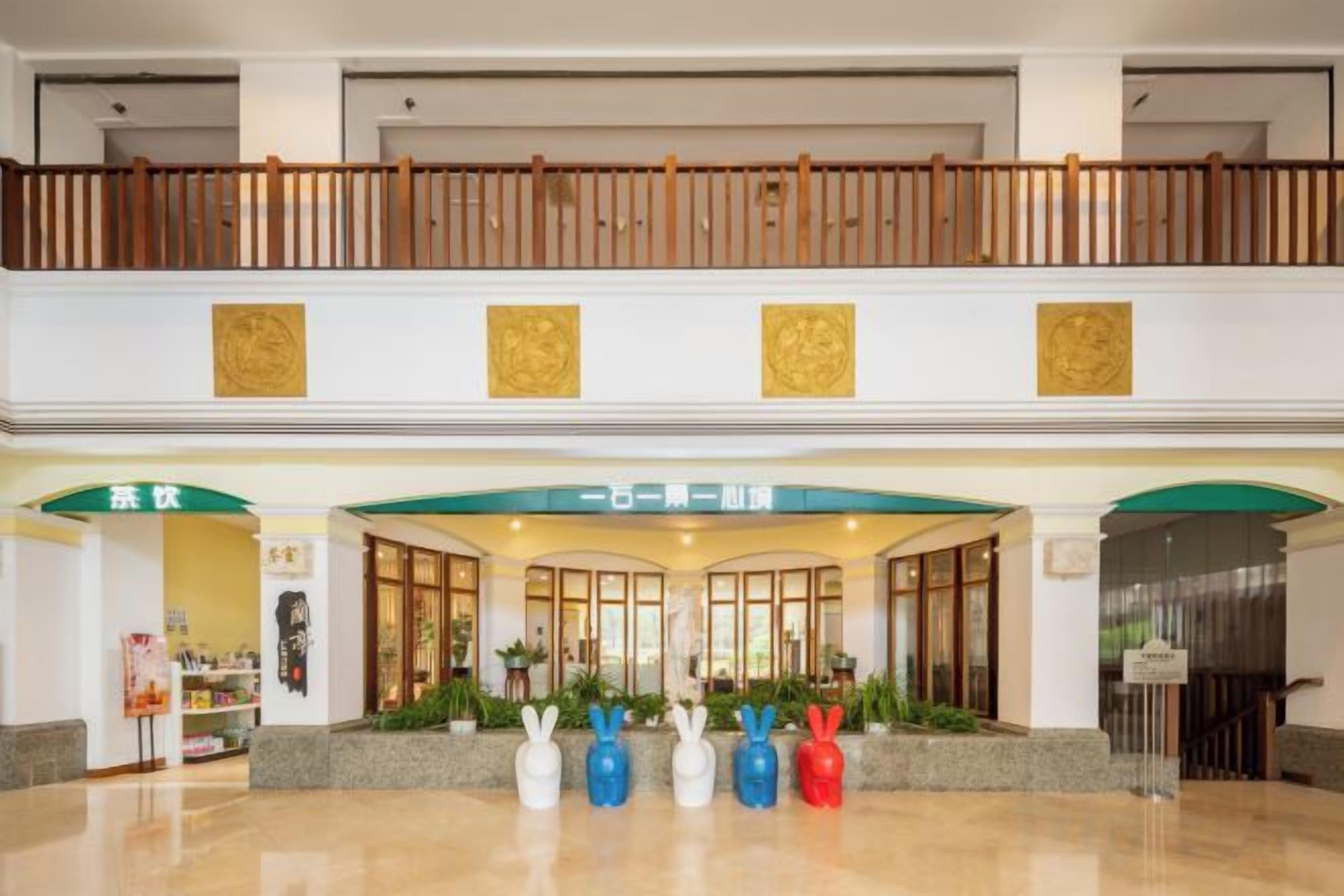 A hotel lobby with a wooden balcony, a reception desk, and a green awning.