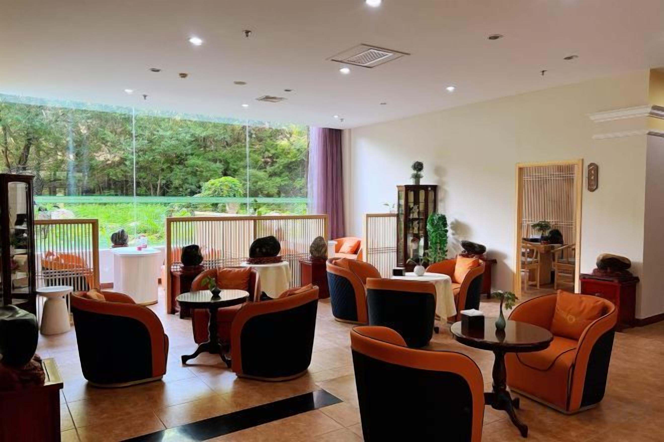 A hotel lobby with seating areas, a reception desk, and a view of a garden.