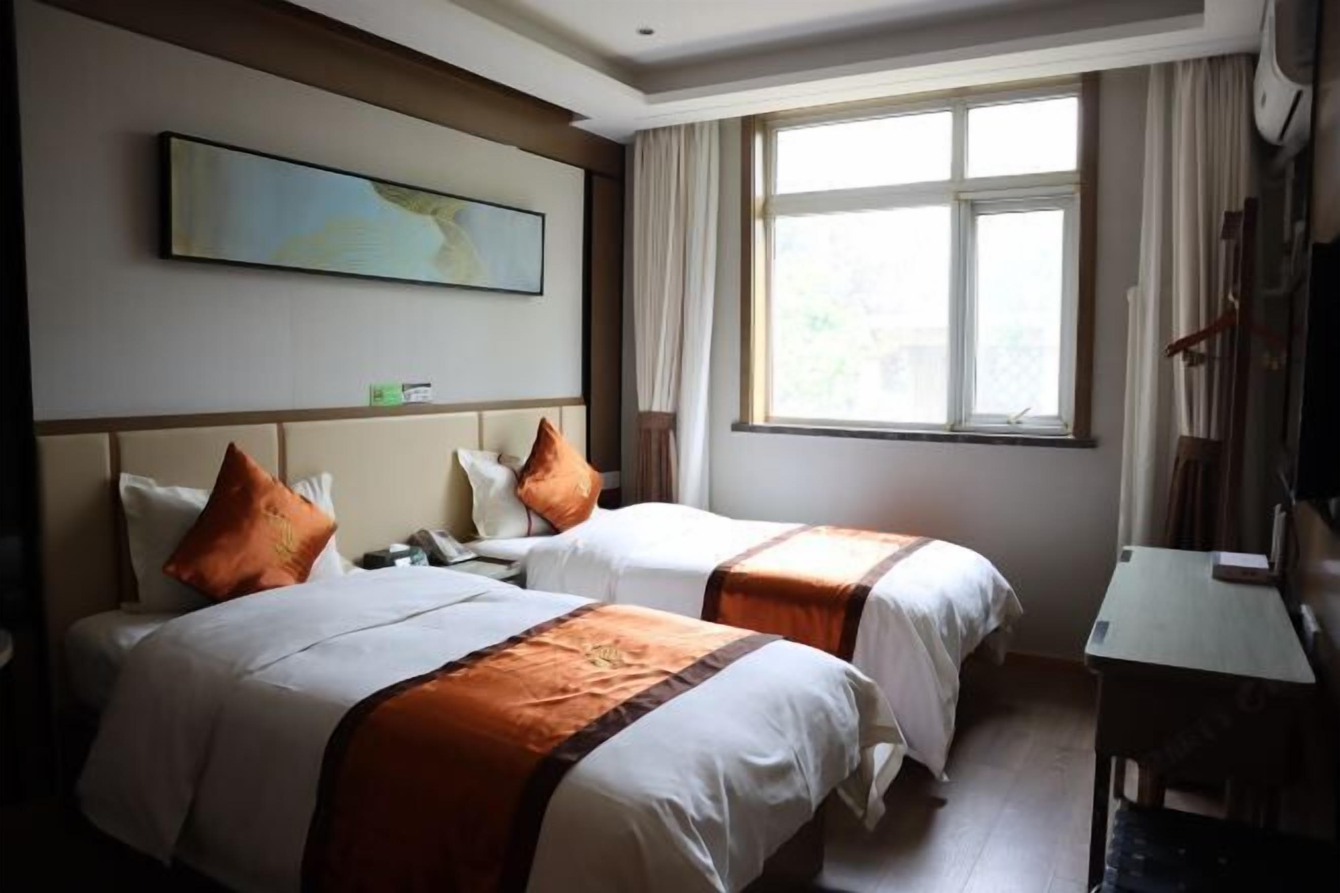 A hotel room with two beds, a large window, a painting on the wall, and a desk.