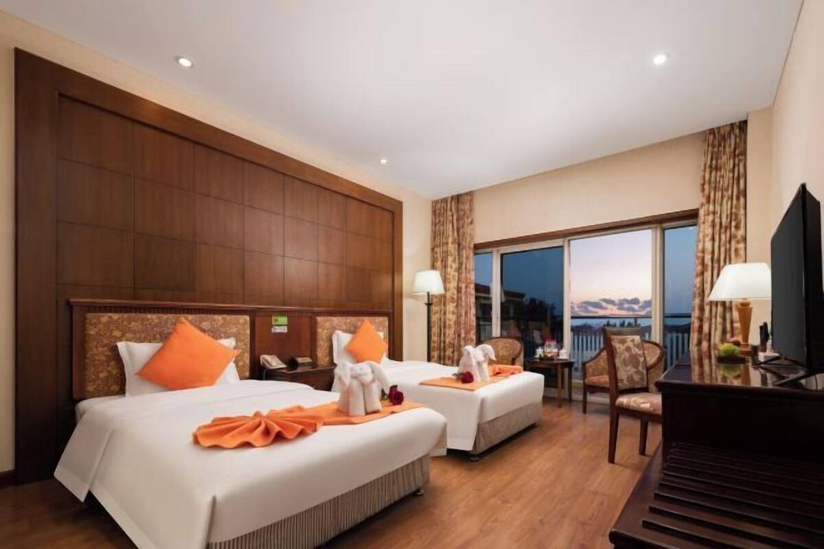 Une chambre d’hôtel avec deux lits, un bureau, une chaise et une vue sur l’extérieur.