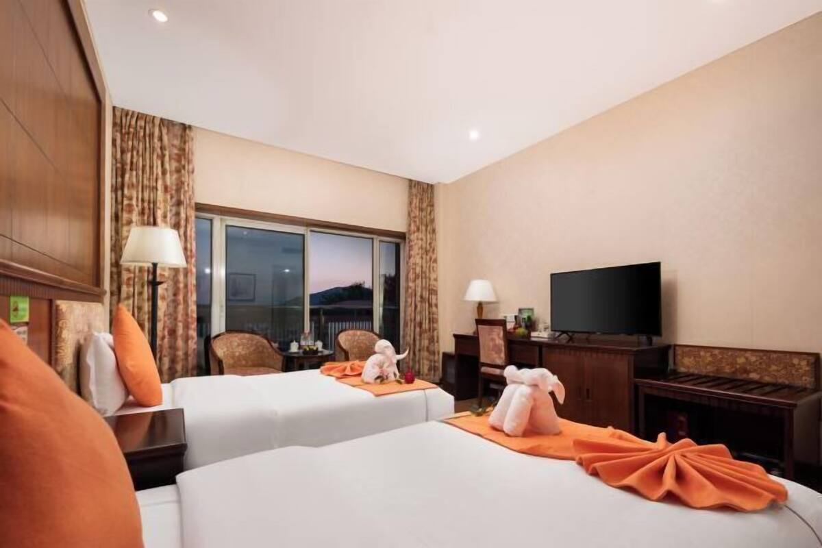 Une chambre d’hôtel avec deux lits, une télévision et une grande fenêtre.