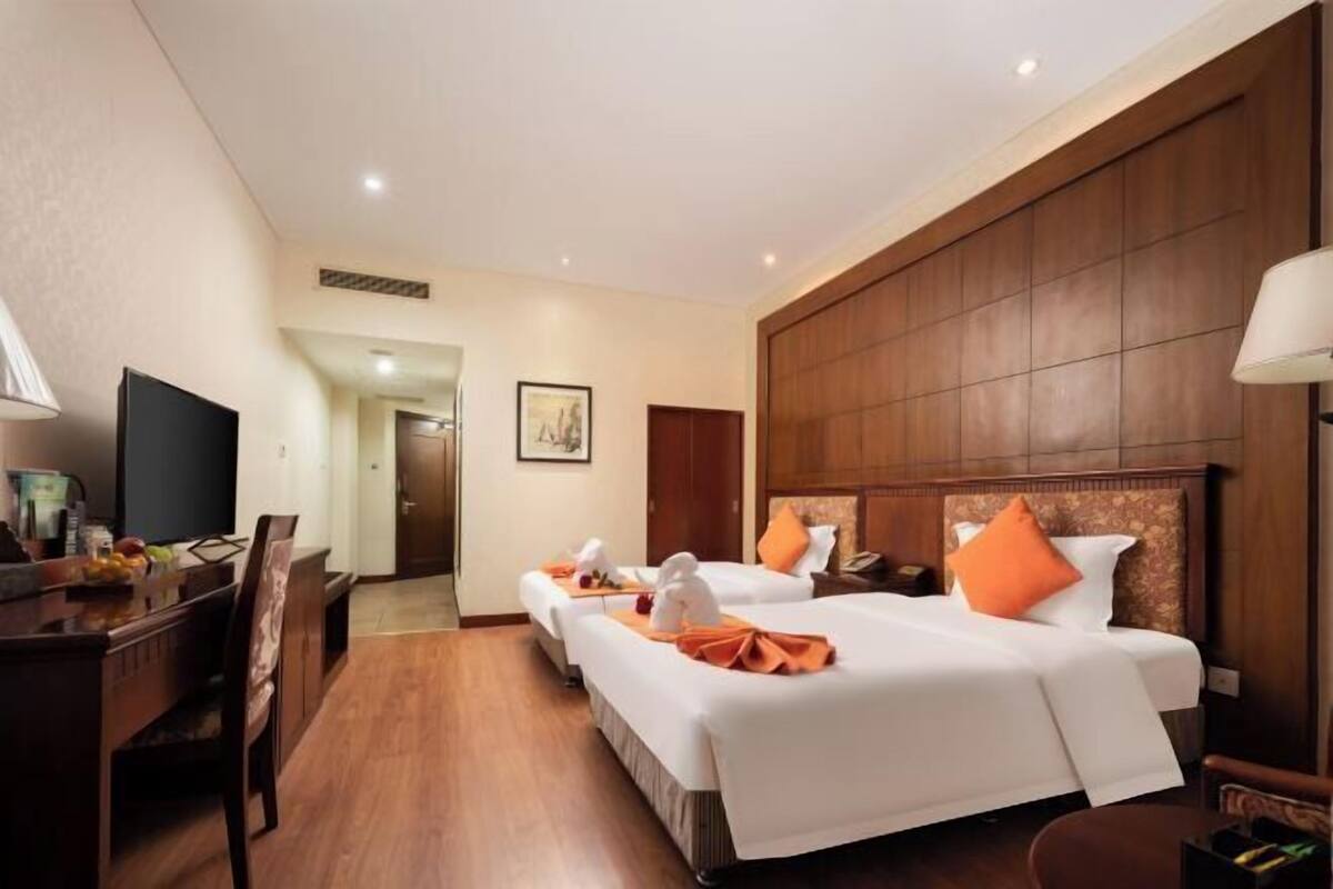 Une chambre d’hôtel avec deux lits, un bureau, une télévision et un coin repas.