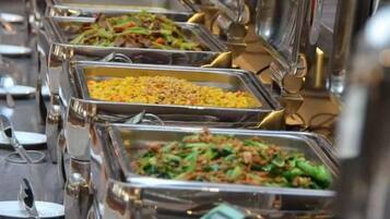 Un bufé con diversas opciones de comida en bandejas de metal.