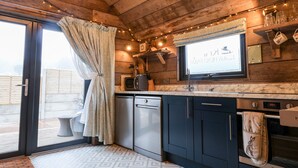 A rustic kitchen with wooden walls, a built-in oven, and a television mounted above the counter. - Sunset Retreat (Scarborough)