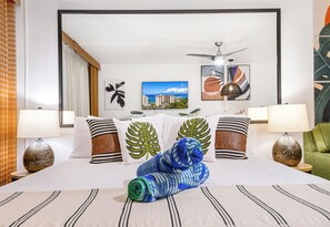 Ein Hotelzimmer mit einem Bett, zwei Lampen, einem Deckenventilator und Kunstwerken an den Wänden.