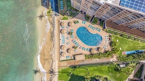 An aerial view of a resort with a large swimming pool, beach, and adjacent hotel buildings. - Ocean Tropics Oasis, Beachfront, King bed, AC/pool (Lahaina)