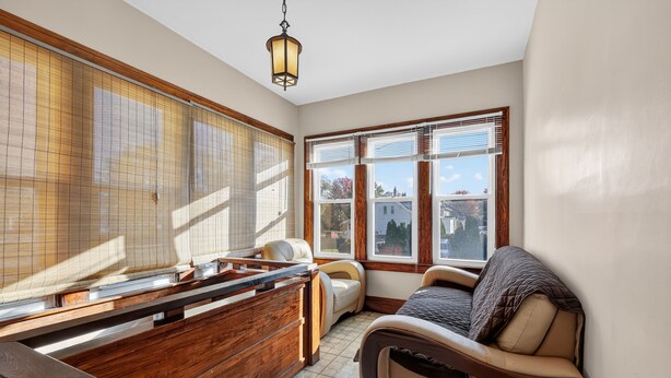 A room with a wooden bench, a cushioned chair, and a bed with a quilted cover. - Carriage House: Perfect for Summer Explorations – Comfortable Loft Living (Wyandotte)