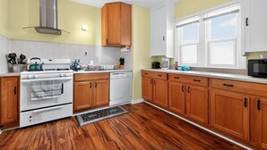 A kitchen with wooden cabinets, a stainless steel range hood, a white stove, and a dishwasher. - Carriage House: Perfect for Summer Explorations – Comfortable Loft Living (Wyandotte)