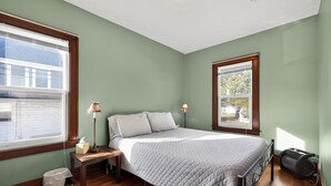 A bedroom with a bed, bedside table, lamp, and a window. - Carriage House: Perfect for Summer Explorations – Comfortable Loft Living (Wyandotte)