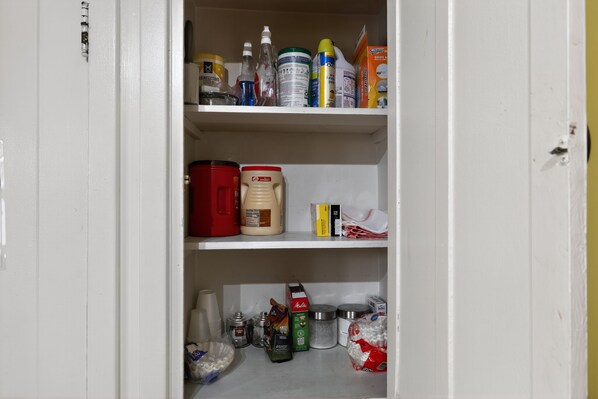Eine Speisekammer mit Regalen, gefüllt mit verschiedenen Lebensmitteln, darunter Dosen, Flaschen und Behältern.