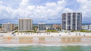 Ein Hotel direkt am Strand mit mehreren Gebäuden, einem Sandstrand und blauem Himmel.