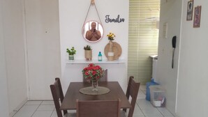 Un comedor con mesa y sillas de madera, un espejo, una estantería con plantas y una pared con un cartel que dice 'Familia'.