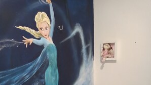 Un dormitorio con una cama, un mural en la pared y una pequeña foto colgada.