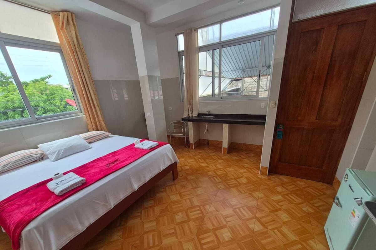 A bedroom with a bed, a desk, and a window.
