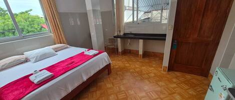 Un dormitorio con cama, escritorio y ventana.