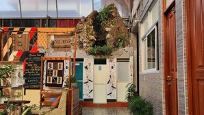 Un hall d’hôtel doté d’un sol carrelé en pierre, d’un grand élément décoratif en roche et de diverses plantes.