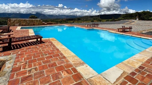 A swimming pool with a brick patio and outdoor furniture, surrounded by a scenic landscape with mountains and a clear sky. - CASA MORANESI (Caucasia)