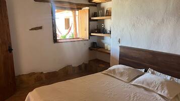 Um quarto com cama, janela, prateleira e porta.
